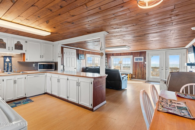 kitchen featuring white cabinets, dishwasher, stainless steel microwave, open floor plan, and a sink