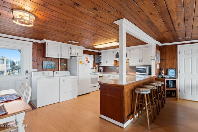 kitchen featuring a peninsula, white appliances, independent washer and dryer, and white cabinets