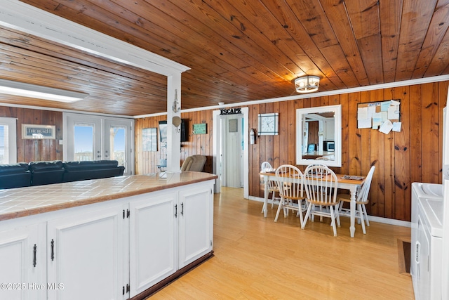 kitchen with tile countertops, wooden ceiling, white cabinets, open floor plan, and french doors