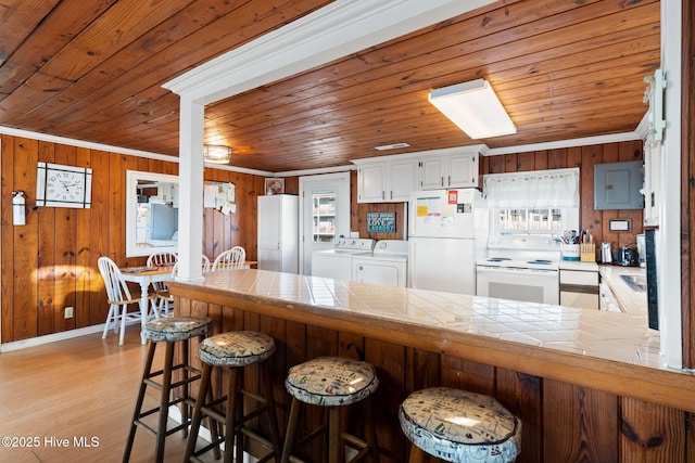 kitchen featuring white appliances, washer and clothes dryer, tile countertops, a peninsula, and white cabinetry