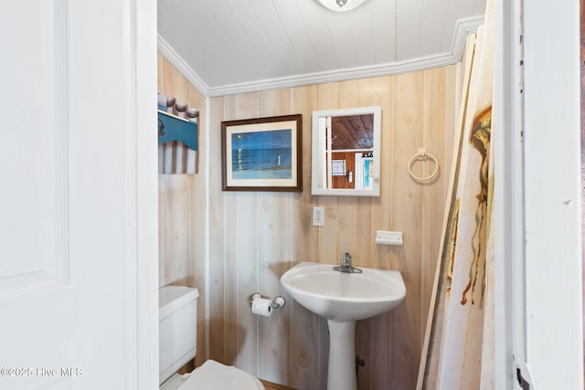 half bathroom with toilet, wooden ceiling, crown molding, and wood walls