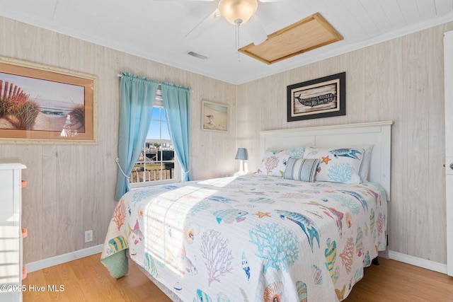 bedroom with ornamental molding, wood finished floors, visible vents, and baseboards