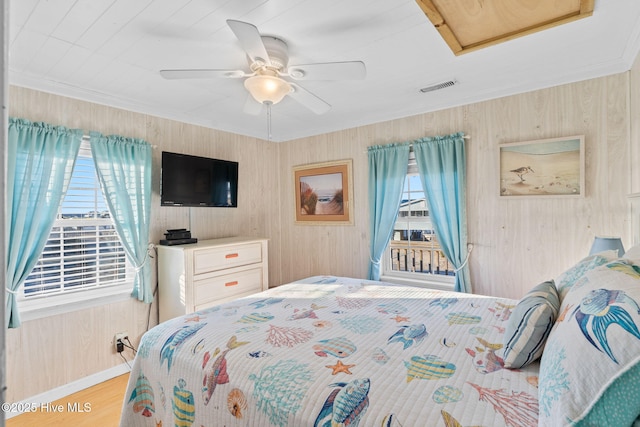 bedroom featuring attic access, visible vents, ceiling fan, wood finished floors, and crown molding