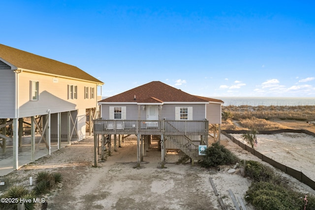 back of property featuring a water view, stairs, a carport, and roof with shingles