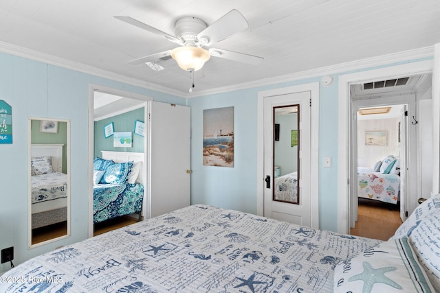 bedroom featuring a ceiling fan, visible vents, crown molding, and wood finished floors