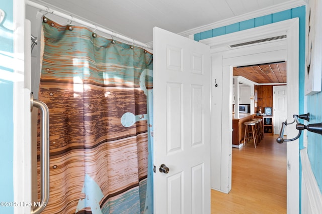 bathroom featuring crown molding, visible vents, wooden walls, wood finished floors, and wooden ceiling