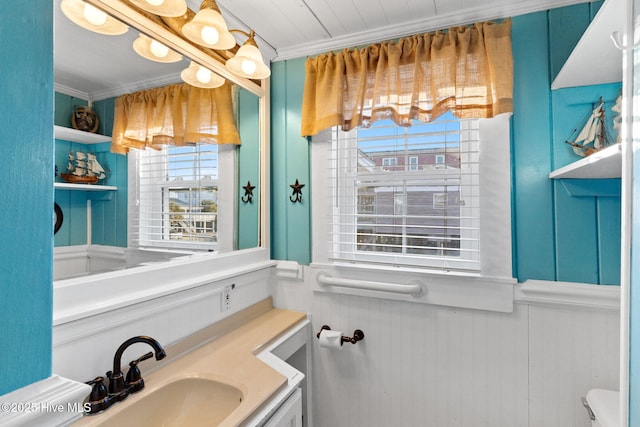 bathroom featuring toilet, ornamental molding, wainscoting, and vanity