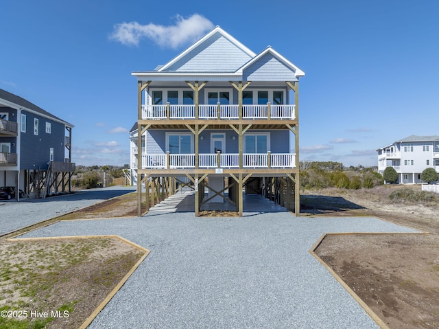 raised beach house featuring a carport, driveway, and a balcony