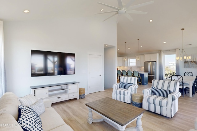 living area featuring ceiling fan with notable chandelier, light wood finished floors, and recessed lighting