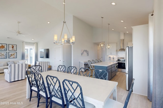 dining area with high vaulted ceiling, light wood-type flooring, recessed lighting, and ceiling fan with notable chandelier