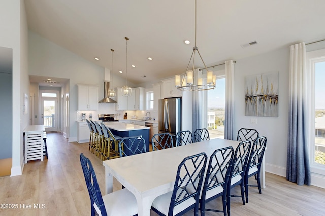 dining area featuring a notable chandelier, light wood-style flooring, visible vents, and a healthy amount of sunlight