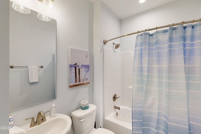 full bath featuring toilet, shower / bathtub combination with curtain, and a sink