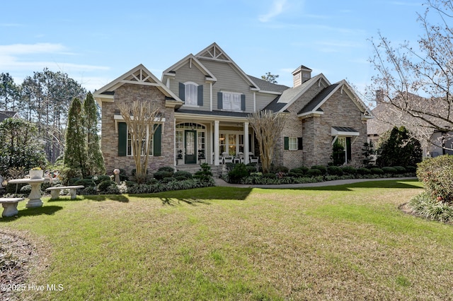 craftsman-style house with a front lawn, a chimney, covered porch, and stone siding