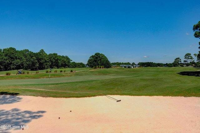 view of property's community featuring view of golf course and a lawn