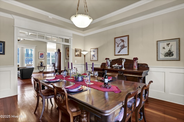 dining room with a decorative wall, wood finished floors, a wainscoted wall, and ornamental molding
