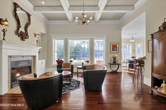 living area featuring a tiled fireplace, wood finished floors, beam ceiling, a chandelier, and coffered ceiling