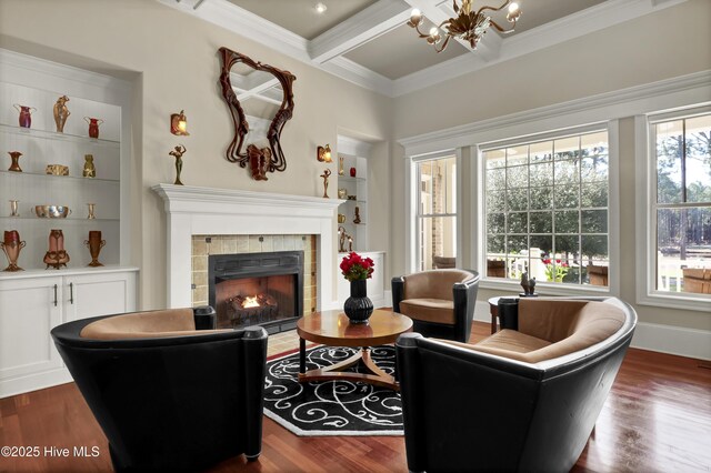 living area with crown molding, a tile fireplace, a chandelier, built in features, and wood finished floors