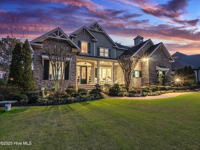 view of front of property featuring stone siding, a front lawn, and a porch