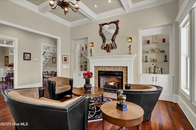 living room featuring dark wood-style flooring, a chandelier, coffered ceiling, built in features, and ornamental molding