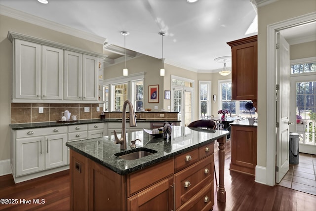 kitchen with a sink, dark wood finished floors, tasteful backsplash, dark stone countertops, and decorative light fixtures