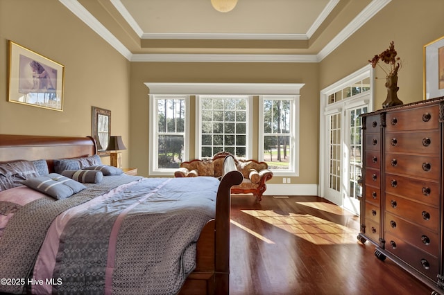 bedroom featuring wood finished floors, a tray ceiling, baseboards, ornamental molding, and access to exterior