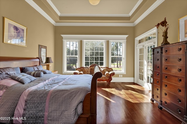 bedroom featuring baseboards, a tray ceiling, ornamental molding, and dark wood-style flooring