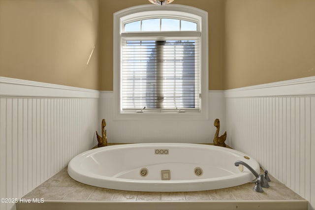 full bathroom featuring a wainscoted wall and a tub with jets