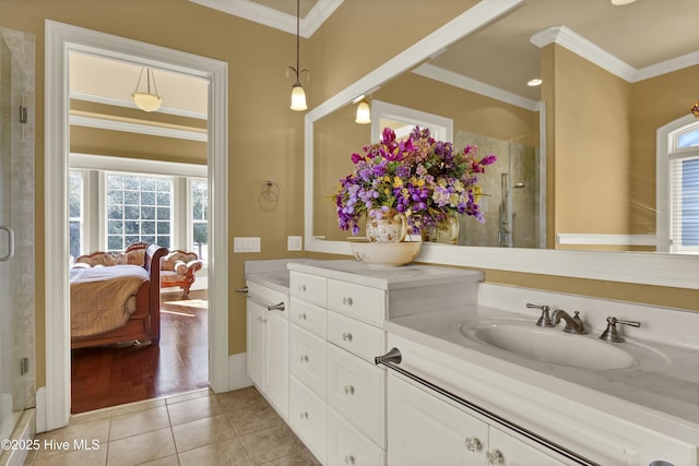 ensuite bathroom with tile patterned flooring, plenty of natural light, a shower stall, ornamental molding, and double vanity