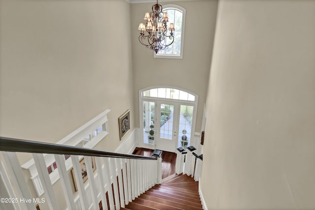staircase featuring a chandelier, wood finished floors, and a high ceiling