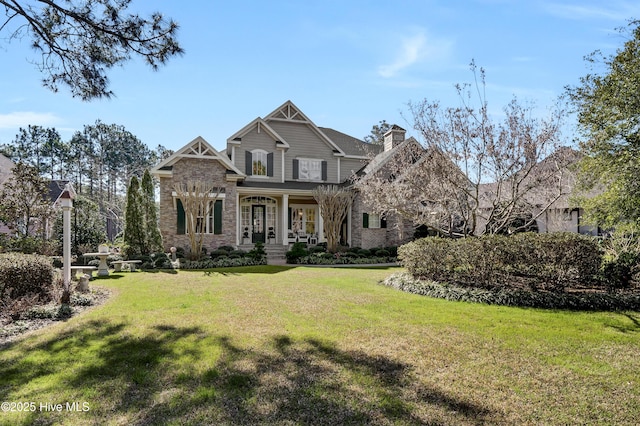 craftsman-style house featuring a front lawn, a chimney, brick siding, and a porch