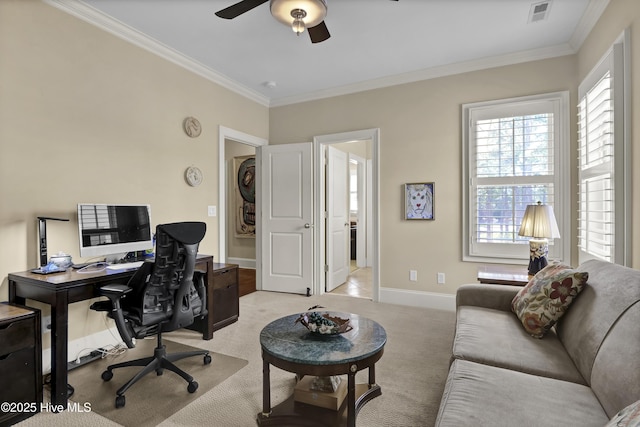 office space with light colored carpet, visible vents, ornamental molding, a ceiling fan, and baseboards