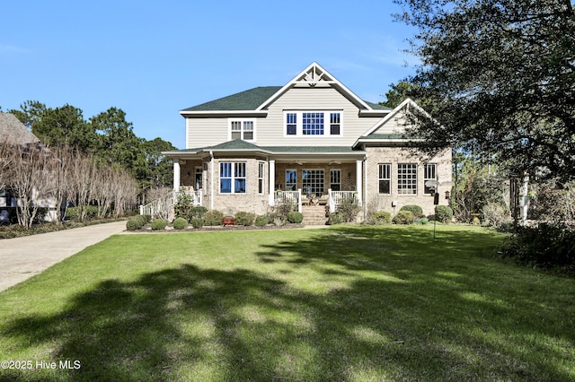 craftsman house with covered porch, brick siding, and a front yard