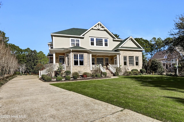 view of front of house featuring a front yard, covered porch, brick siding, and concrete driveway