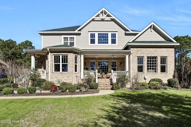 craftsman-style home featuring a porch, brick siding, a front yard, stairway, and ceiling fan