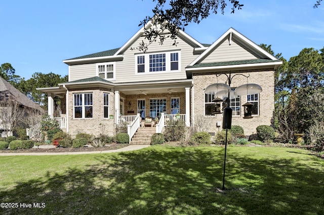 craftsman house featuring a porch, brick siding, a front yard, and stairway