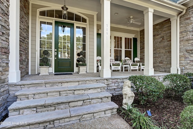 doorway to property with ceiling fan, stone siding, a porch, and brick siding