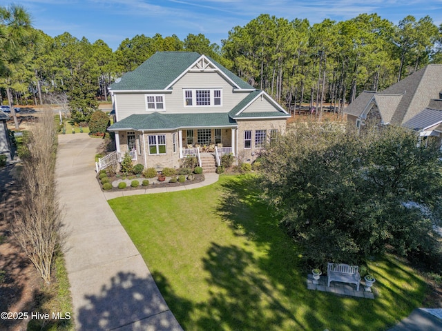 view of front of home featuring covered porch, roof with shingles, and a front yard