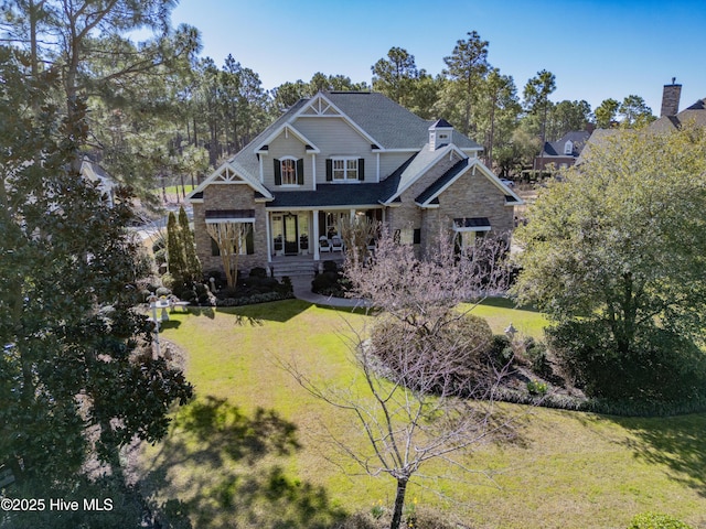 craftsman house featuring covered porch, stone siding, and a front yard