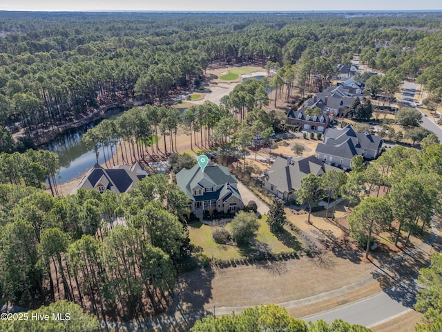 aerial view of property's location with a forest, a large body of water, and nearby suburban area