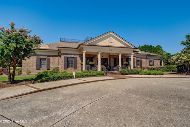 greek revival inspired property featuring brick siding and a porch