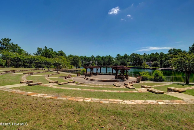 surrounding community featuring a water view, a yard, and view of wooded area