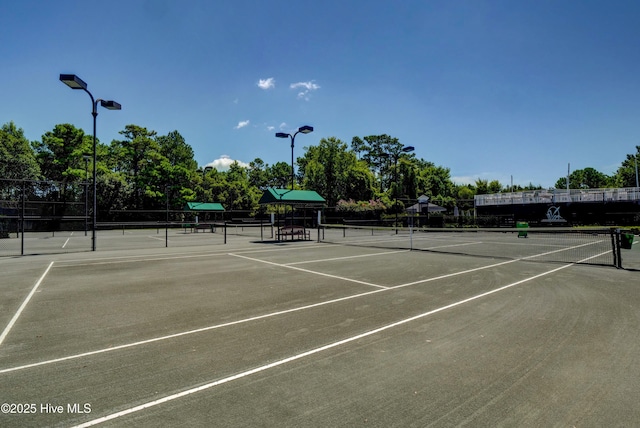 view of tennis court with fence and view of wooded area