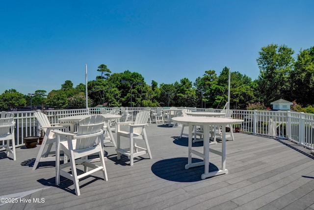 wooden terrace with outdoor dining area, view of wooded area, and an outbuilding