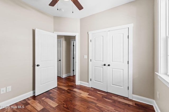 unfurnished bedroom with a closet, dark wood finished floors, baseboards, and ceiling fan