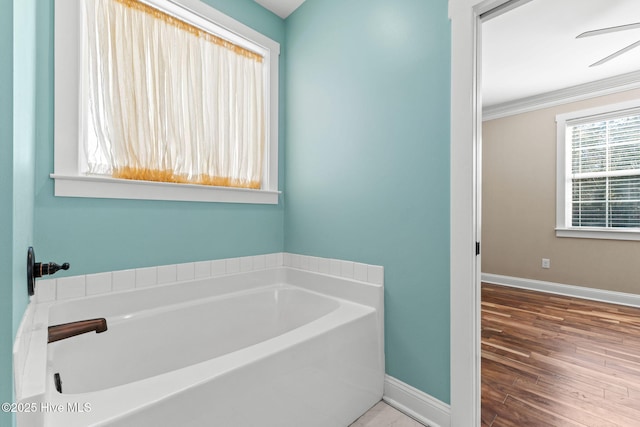 full bathroom featuring crown molding, wood finished floors, a bath, and baseboards