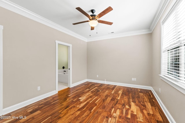 spare room with visible vents, baseboards, ceiling fan, wood finished floors, and crown molding