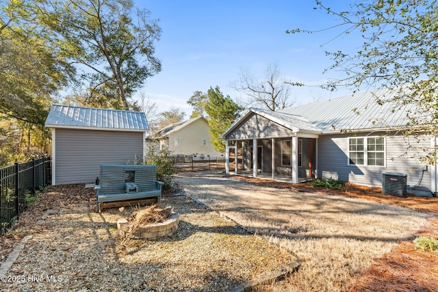 rear view of property with metal roof, a fenced backyard, a sunroom, and central air condition unit