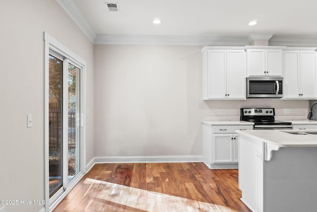 kitchen featuring stainless steel appliances, light countertops, visible vents, white cabinets, and wood finished floors