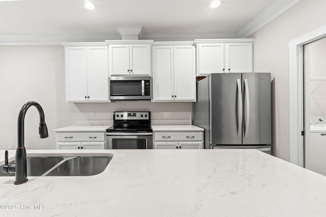 kitchen with appliances with stainless steel finishes, light stone counters, crown molding, white cabinetry, and a sink