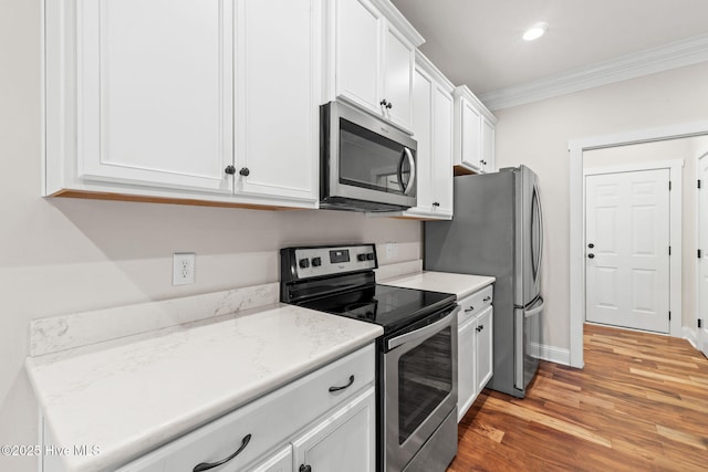 kitchen featuring recessed lighting, appliances with stainless steel finishes, ornamental molding, white cabinets, and light wood-type flooring